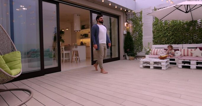 man opens sliding doors, going out on rooftop patio with cozy lounge zone