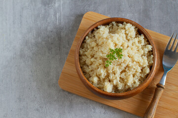 Composition with cooked quinoa in bowl and wooden fork on table