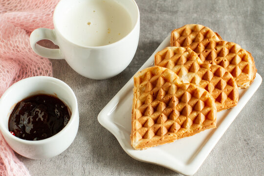 Heart-shaped waffles with strawberry jam and cappuccino