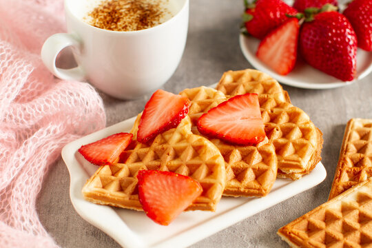 Heart-shaped waffles with strawberry jam and cappuccino