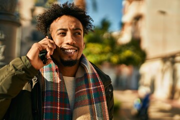 Young african american man smiling happy talking on the smartphone at the city