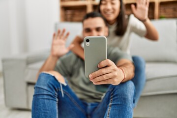 Young latin couple smiling happy having video call using smartphone at home.