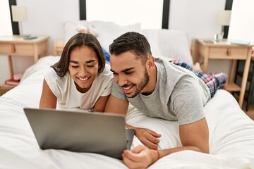 Young latin couple smiling happy using laptop at bedroom