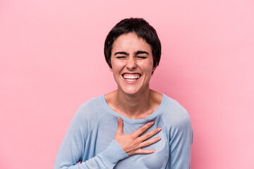 Young caucasian woman isolated on pink background laughs out loudly keeping hand on chest.