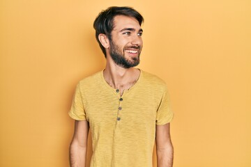 Young hispanic man wearing casual clothes looking away to side with smile on face, natural expression. laughing confident.