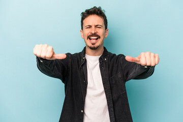 Young caucasian man isolated on blue background raising both thumbs up, smiling and confident.