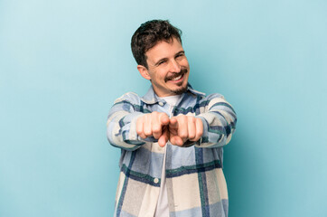 Young caucasian man isolated on blue background pointing to front with fingers.
