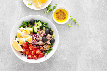 Tuna and fresh vegetable salad of tomato, cucumber, olives, onion,  lettuce and boiled egg, top view