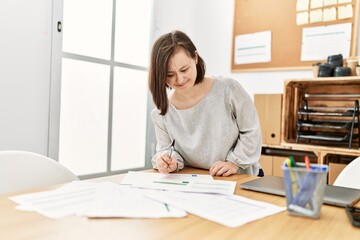 Brunette woman with down syndrome working with documents at business office