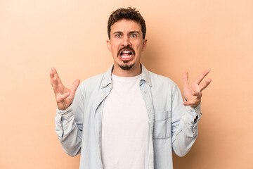 Young caucasian man isolated on beige background screaming to the sky, looking up, frustrated.
