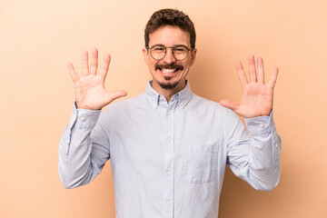 Young caucasian man isolated on beige background showing number ten with hands.