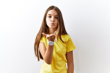 Young brunette teenager standing together over isolated background looking at the camera blowing a kiss with hand on air being lovely and sexy. love expression.