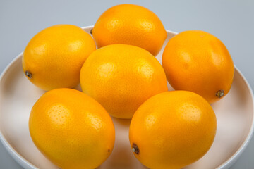Lemons in round plate on white background
