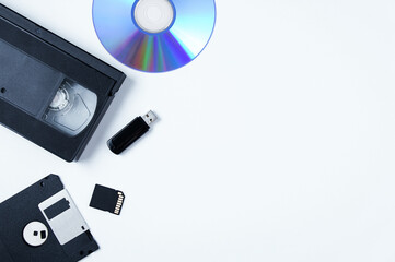 Video cassette, flash drive, memory card, CD, floppy disk. White background. Place text.