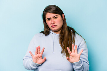 Young caucasian overweight woman isolated on blue background rejecting someone showing a gesture of disgust.