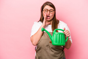 Young gardener caucasian overweight woman holding watering can isolated background is saying a secret hot braking news and looking aside