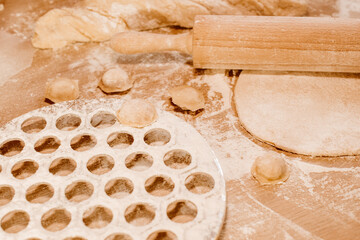 Making homemade dumpling dough. The rolling pin rolls out dough, flour and a mold for dumplings or ravioli. Home cooking food. National cuisine