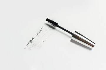 Mascara lies on a white background, and leaves a black mark showing how the brush works. Cosmetics and make-up personal care - obrazy, fototapety, plakaty