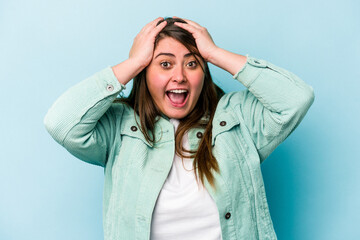 Young caucasian overweight woman isolated on blue background screaming, very excited, passionate, satisfied with something.