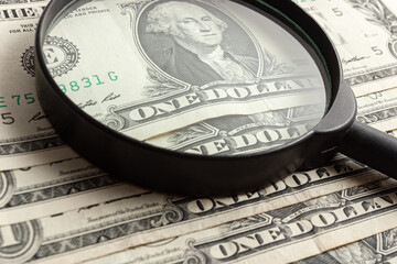 Portrait of George Washington on one US dollar banknote through a magnifying glass. Several American dollar bills close up. Bundle of USA cash.