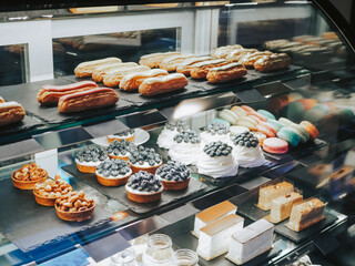 A lot of different desserts and sweets on display. Delicious pastries in the coffee shop. Variety of cakes, eclairs and cakes