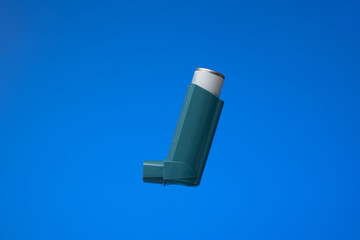Asthma inhaler, generic, non-branded. Close up studio shot, isolated on blue background
