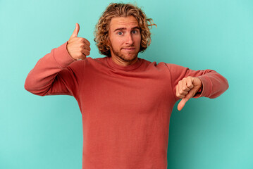 Young caucasian man isolated on blue background showing thumbs up and thumbs down, difficult choose...