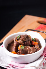 Food concept French red wine beef stew bourguignon on wooden board with copy space