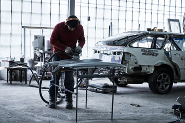 Car service worker repairs restores car