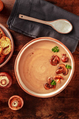 Mushroom soup, shot from above on a dark wooden background with a rustic spoon