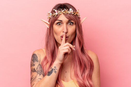 Young caucasian elf woman isolated on pink background keeping a secret or asking for silence.