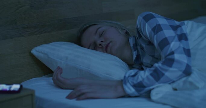 beautiful girl sleeps in bed, wakes up from a notification on a smartphone