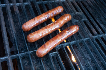 Three Hot Dogs Cooking on an Outdoor Gas Grill