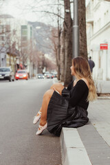 A woman sitting on the pavement in a dancing outfit.