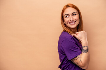 Obraz premium Young caucasian woman isolated on beige background points with thumb finger away, laughing and carefree.
