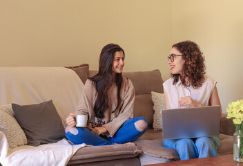 Young women working from home sitting in a sofa using laptop