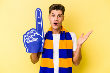 Young sports fan man isolated on yellow background surprised and shocked.