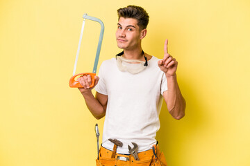Young electrician caucasian man isolated on yellow background.showing number one with finger.