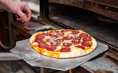 chef baker making pizza at kitchen. Put on landing shovel and send it to the oven.