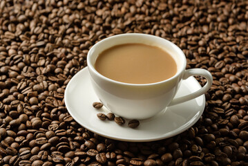a cup of coffee with milk close-up on the background of coffee beans.