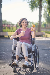 A woman with a phone in hands looking happy and smiling