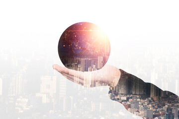 Double exposure of hand holding globe with growing light with city scape for global business...