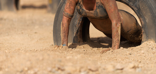 Mud race runners.The participante overcoming the obstacle made of tires
