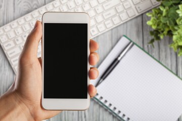 Male hand holding a smartphone with a blank screen