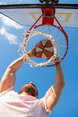 man dunking basketball ball through net ring with hands, sport success © Olena