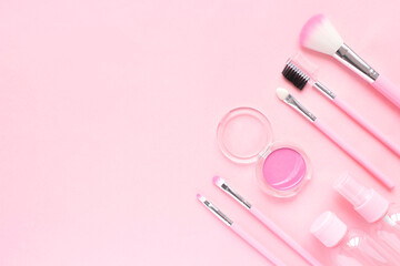 Obraz na płótnie Canvas Delicate composition for the beauty sphere: makeup brushes, shadows, cream jars on a pink background. Layout for a beauty blogger or makeup artist. Flat lay, top view