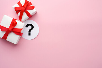 White boxes with gifts on a pink background. St. Valentine's Day. Question mark on white sheet. Concept of love and spring. Top view, background, copy space