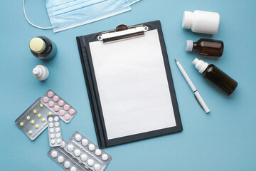 Tablet for writing with an empty white sheet and a pen. Blisters with tablets. The concept of medical prescriptions and drug prescriptions. Mock up doctor's desk
