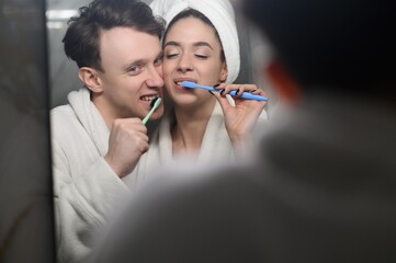 a young married couple brushing their teeth together. Dental hygiene.
