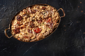 Risotto ai funghi, mushroom risotto, rustic rice with mushrooms, shot from above on a black background with copy space